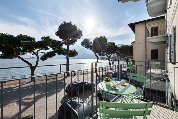 A balcony with a table and chairs, overlooking a body of water and trees.