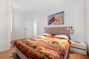 Une chambre à coucher avec un lit, une table de chevet, une lampe fixée au mur et une porte.