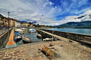 Une promenade en bord de mer, avec des bateaux amarrés, un pavé de pierre et une vue sur les montagnes.