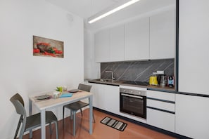 Una cocina moderna con armarios blancos, encimera negra, estufa y fregadero.