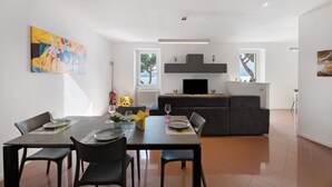 Een moderne woonkamer met een eethoek, een bank, een flatscreen televisie en kunstwerken aan de muren.