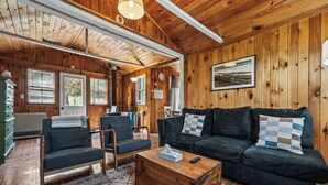 A wooden interior with a sofa, chairs, a wooden chest, and a lamp. - RC 17 – Cozy Cabin with Shared Rangeley Lake Waterfront, Kayaks, Paddleboards & Firepit (Rangeley)