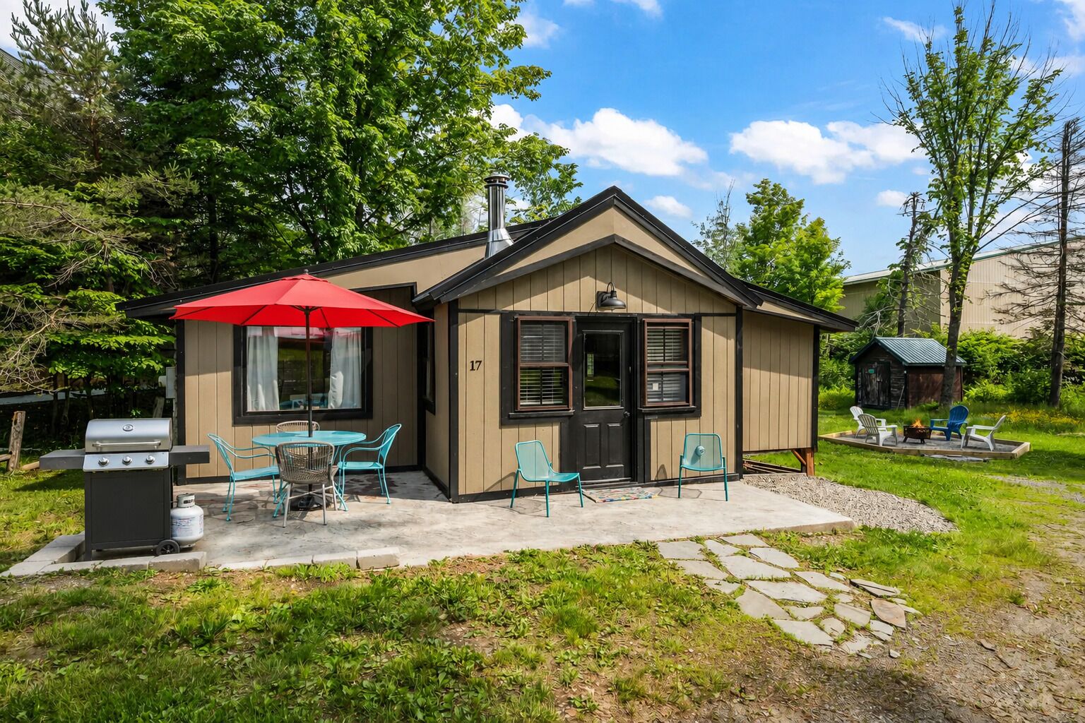 A small cabin with a patio, outdoor seating, and a grill.