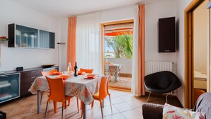 Un coin repas avec une table dressée pour quatre personnes, une chaise noire et une vue sur l’extérieur.
