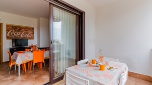Un coin repas avec une table dressée pour deux personnes, un canapé et un téléviseur en arrière-plan.