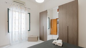A bedroom with a bed, a mirror, a wardrobe, and a small bedside table.