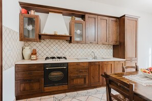 A kitchen with wooden cabinets, a stove, oven, and a sink.