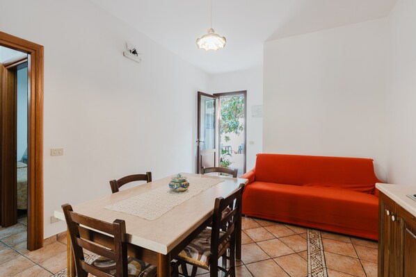 Un espace repas comprenant une table, des chaises, un canapé rouge et un luminaire suspendu.