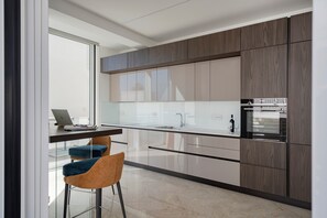 Una cucina moderna con un portatile sul bancone, una bottiglia di vino e un frigorifero.