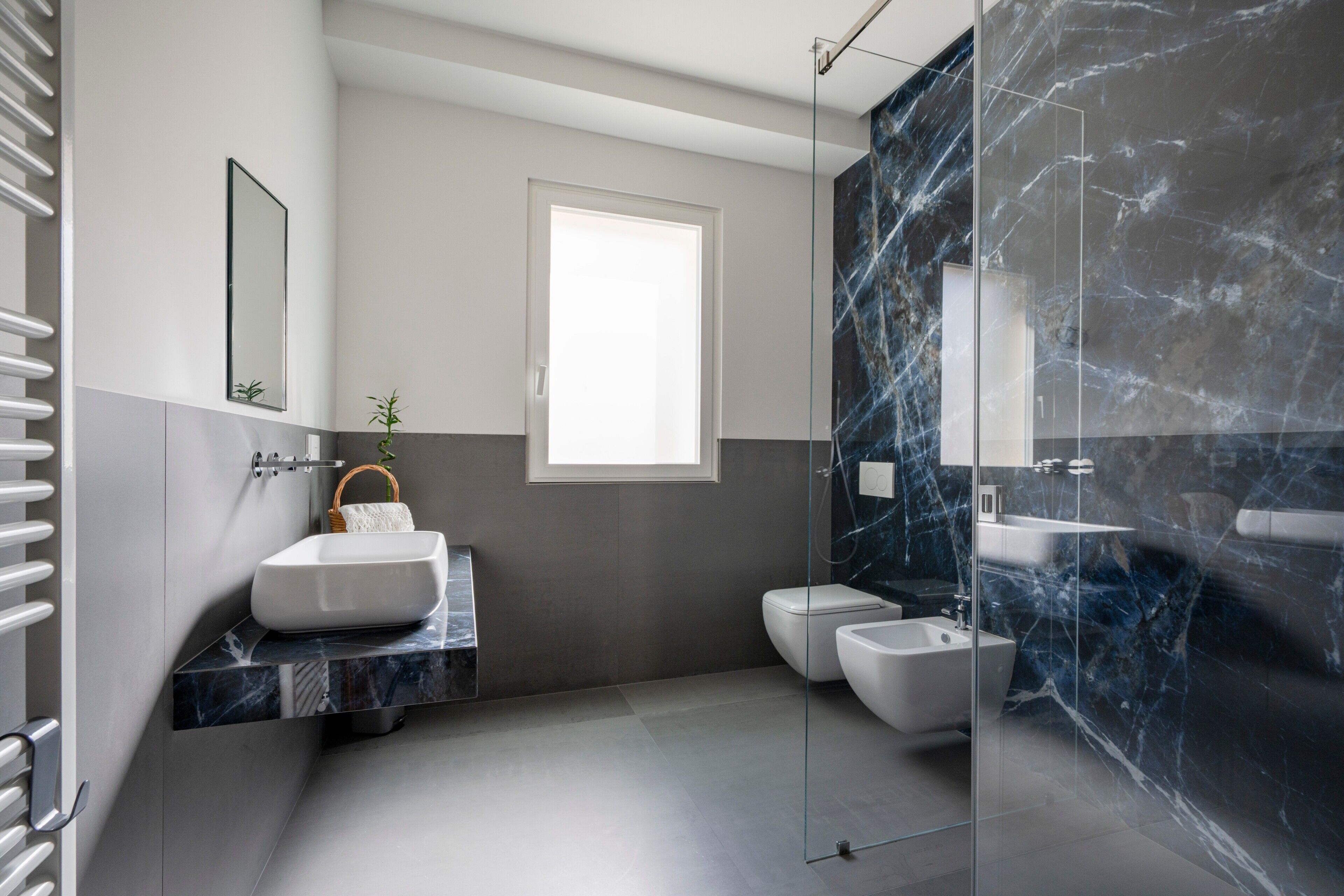 A modern bathroom with a large mirror, a white sink, a bidet, and a glass-enclosed shower.