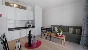 A compact living space with a kitchenette, dining area, and a sofa. - Apartment 'Playa Azul - 6' with Sea View, Private Terrace and Wi-Fi (Vallehermoso)