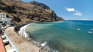 A coastal area with a rocky cliff, clear blue sea, and a building with outdoor seating. - Apartment 'Playa Azul - 6' with Sea View, Private Terrace and Wi-Fi (Vallehermoso)