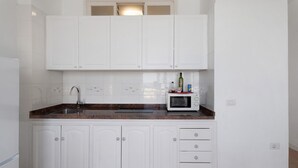 A kitchen with white cabinets, a granite countertop, a sink, a microwave, and a bottle of olive oil. - Apartment 'Playa Azul - 6' with Sea View, Private Terrace and Wi-Fi (Vallehermoso)