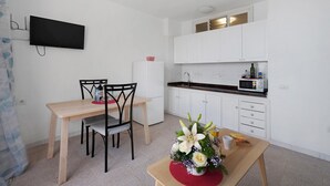 Una cocina moderna con armarios blancos, un microondas y un televisor de pantalla plana montado en la pared.