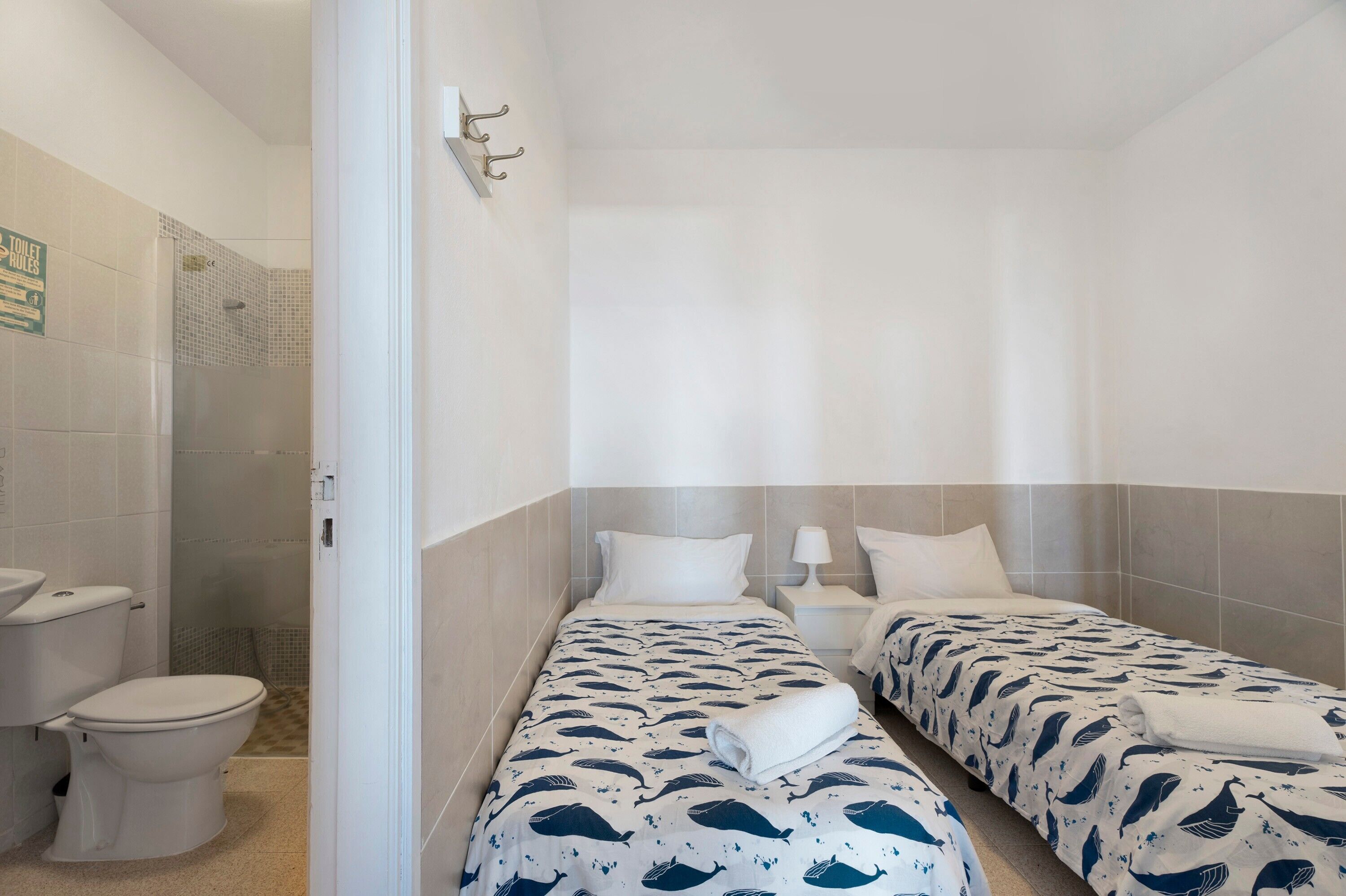 A hotel room with two beds, a shower, and a toilet.