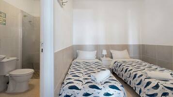 A hotel room with two beds, a shower, and a toilet.
