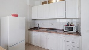 A kitchen with white cabinets, a stainless steel sink, a microwave, and a refrigerator.