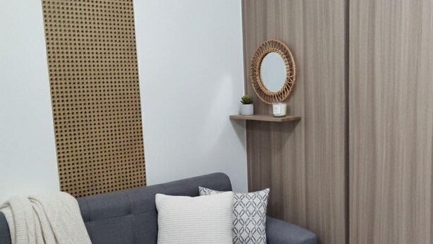 A grey sofa with a white throw blanket, a patterned pillow, and a woven basket. - Mall Of Asia - Aseana Shore Residences (Pasay)