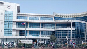 A modern building with multiple floors, large windows, and a flag. - Mall Of Asia - Aseana Shore Residences (Pasay)