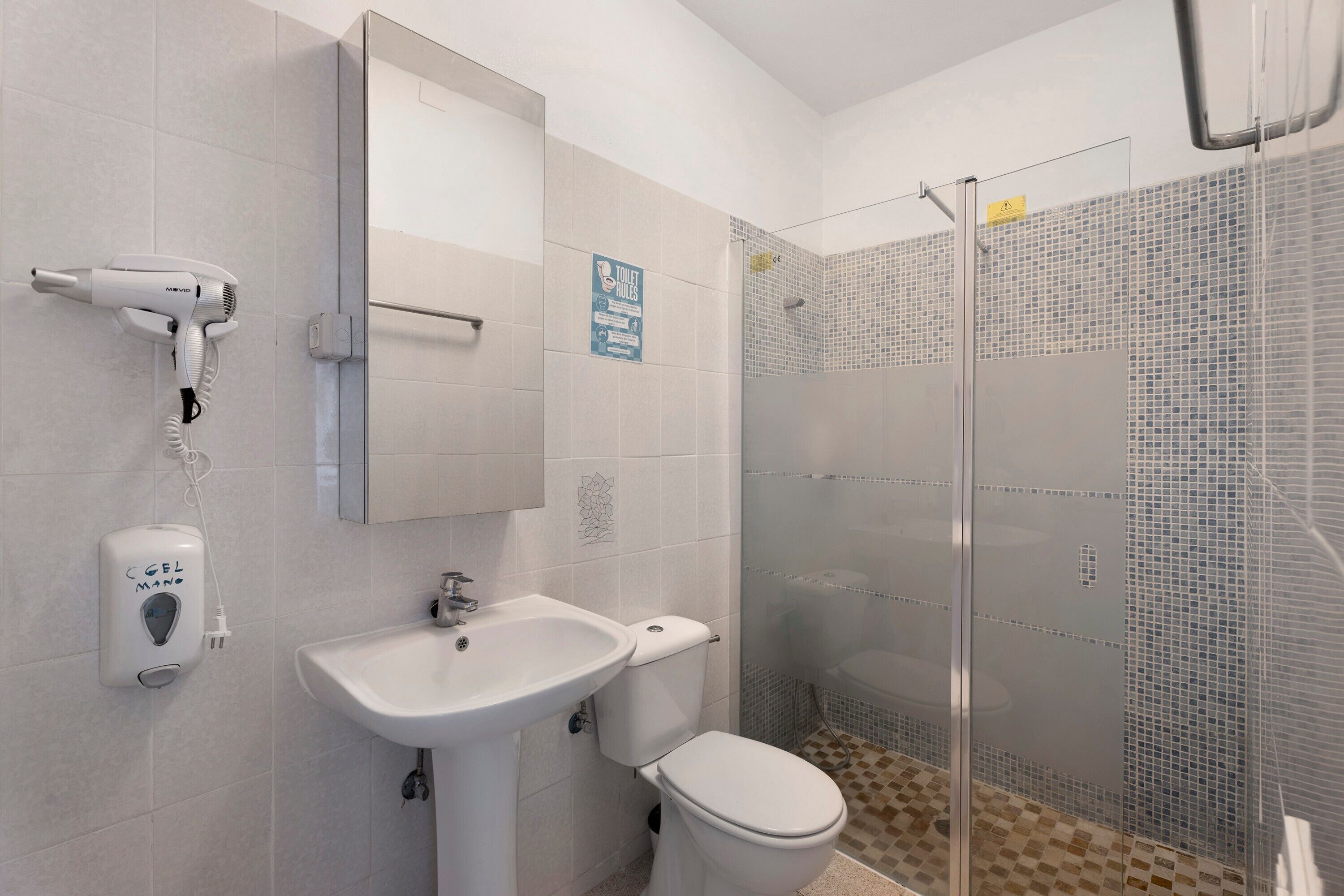 A bathroom with a white sink, toilet, and a glass shower enclosure.