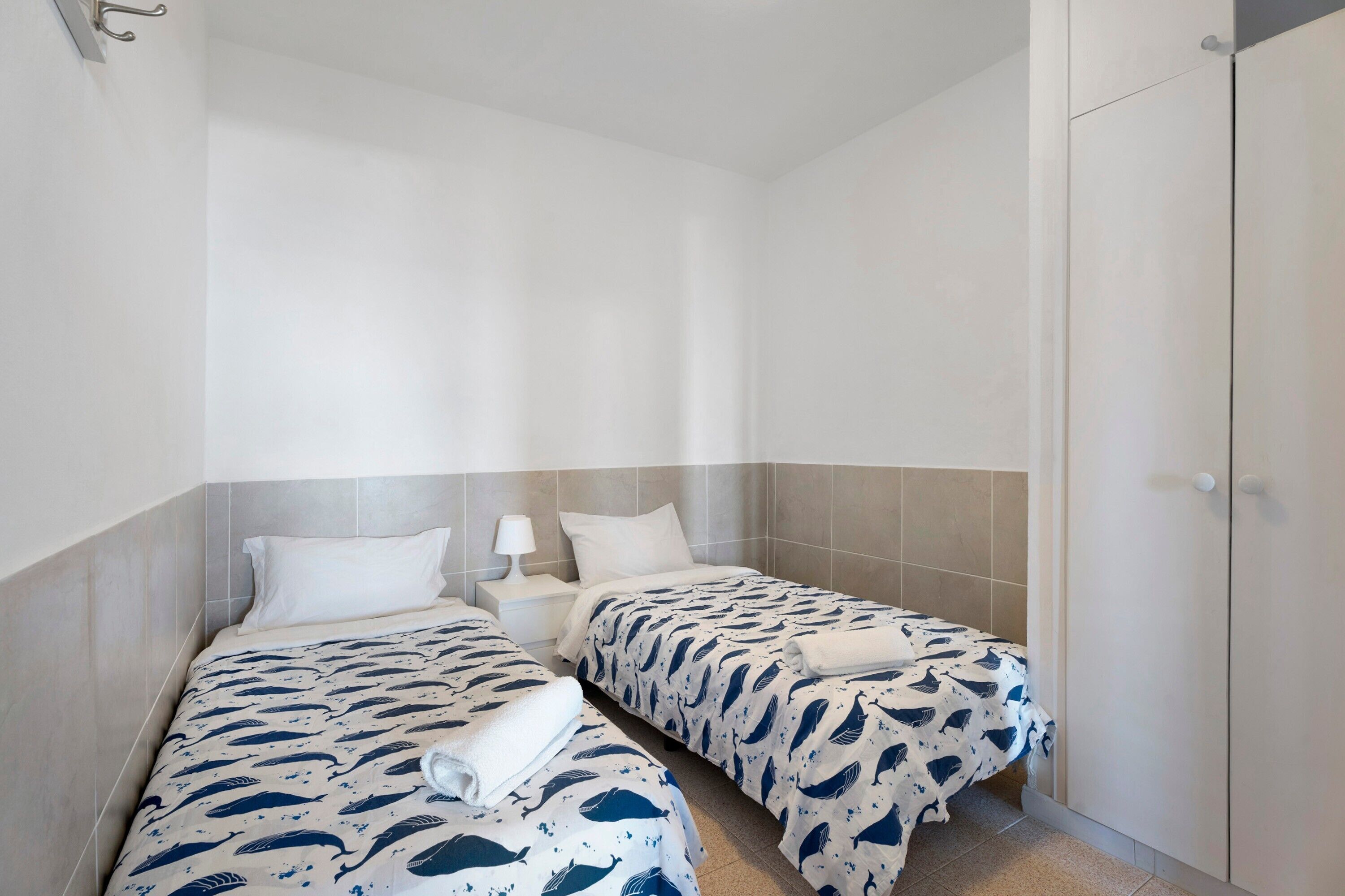 Ein Hotelzimmer mit zwei Betten, einem Nachttisch, einer Lampe und einem Kleiderschrank.