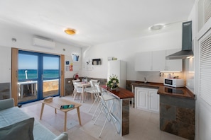 A modern kitchen with a view, white cabinets, a microwave, and a dining area with chairs and a table.