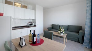A modern kitchen with white cabinets, a microwave, and a dining area with a table, chairs, and a red placemat. - Apartment 'Playa Azul - 7' with Sea View, Private Terrace and Wi-Fi (Vallehermoso)