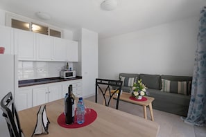 Un espacio habitable compacto con kitchenette, comedor y sofá.