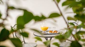 Une table avec un verre de jus d’orange et des croissants, entourée de chaises en métal.