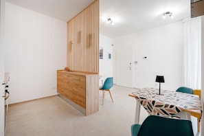 A modern kitchen with wooden cabinets, a dining area with a patterned tablecloth, and a blue chair.