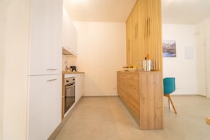 A compact kitchen with white cabinets, a wooden island, and a teal chair. - Room 'Volutta' with Shared Terrace, Wi-Fi and Air Conditioning (Conversano)
