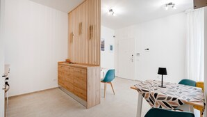 A modern kitchen with wooden cabinets, a dining area with a patterned tablecloth, and a blue chair. - Room 'Volutta' with Shared Terrace, Wi-Fi and Air Conditioning (Conversano)
