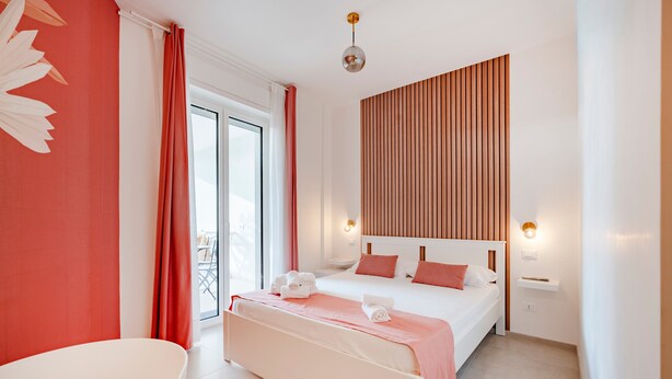 A modern bedroom with a large bed, a bedside table, a chair, and a view of the outdoors. - Room 'Volutta' with Shared Terrace, Wi-Fi and Air Conditioning (Conversano)