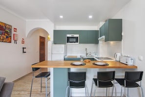 A compact kitchen with a central island, a refrigerator, a microwave, and a toaster.