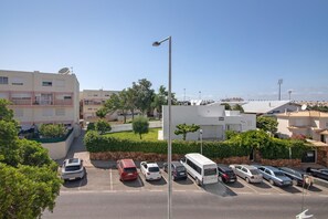 Un estacionamiento con varios automóviles y un autobús, rodeado de edificios y vegetación.
