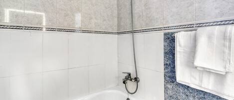 A bathroom with a bathtub, a shower, and a towel rack.
