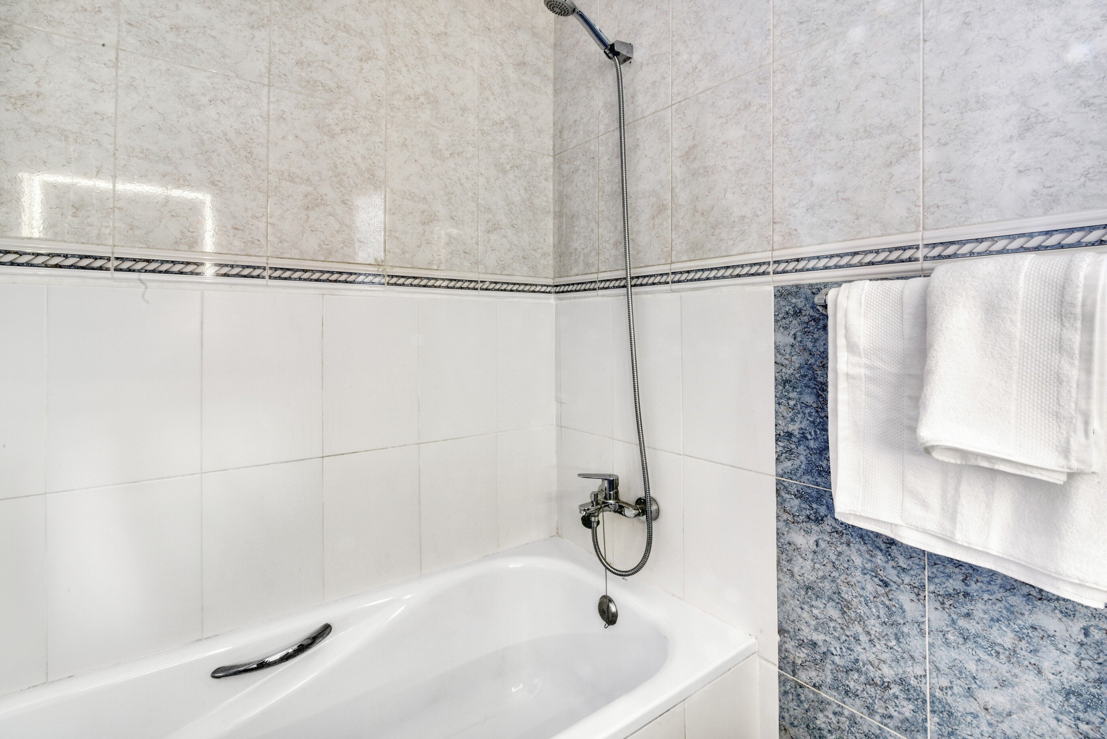 Un baño con bañera, ducha y toallero.