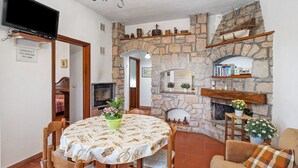 Una habitación acogedora con chimenea de piedra, un televisor montado en la pared y una mesa de comedor con sillas.