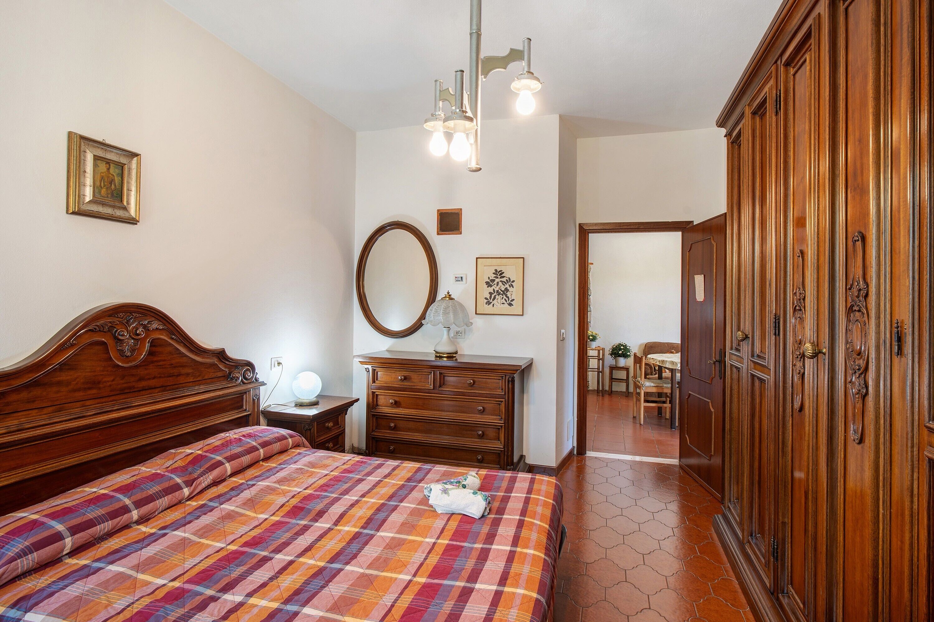 Un dormitorio con cama de madera, cómoda, espejo y armario.