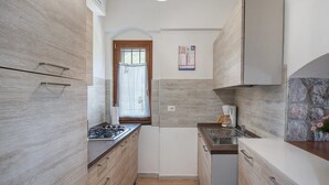 Una cocina compacta con armarios de madera, estufa a gas, cafetera y una pared de acento de piedra.