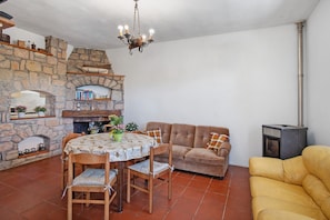 Una sala de estar acogedora con chimenea de piedra, una mesa de comedor con sillas, un sofá y un sillón amarillo.