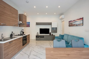Una cocina moderna con armarios de madera, estufa integrada y televisor de pantalla plana.