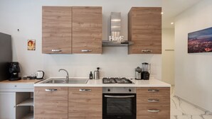 Eine moderne Küche mit Holzschränken, einer Edelstahl-Dunstabzugshaube, einem eingebauten Backofen und einer Marmorarbeitsplatte.