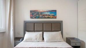 Ein Schlafzimmer mit einem Bett, zwei Nachttischen, einem Beistelltisch und einem Bild an der Wand.