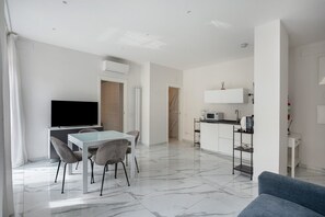 A modern living space with a dining area, kitchen, and a flat-screen TV.
