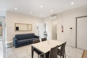 A modern hotel room with a dining area, a sofa, a table, and a mirror. - Apartment 'Family  - Zona Lungomare' with Balcony, Wi-Fi and Air Conditioning (Napoli)