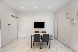 Un comedor moderno con televisor de pantalla plana, suelo de mármol y diseño minimalista.