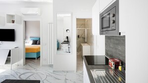 Una habitación de hotel moderna con cama, escritorio, televisor, microondas y baño.