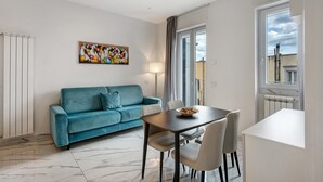 Una sala de estar moderna con un sofá color turquesa, una mesa de comedor y un cuadro en la pared.