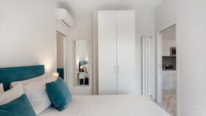 Un dormitorio con una cama, un armario, un espejo y una puerta que da a un baño.